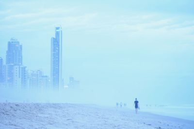 Rear view of man walking on sea during winter