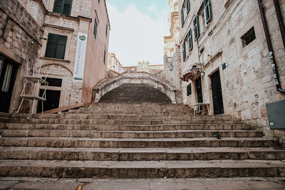 Low angle view of staircase amidst buildings against sky