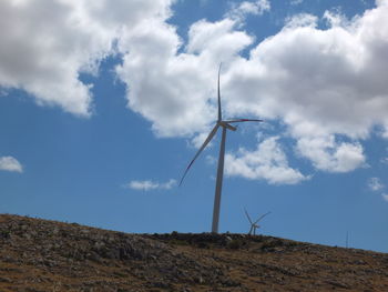 Low angle view of windmill on field against sky