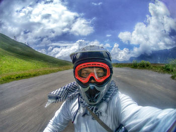 Portrait of man riding motorcycle on road against sky