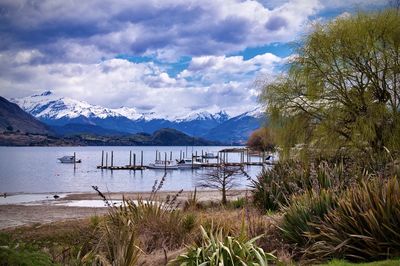 Scenic view of lake by snowcapped mountains against sky