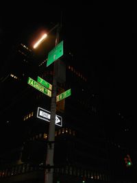 Low angle view of illuminated road sign at night