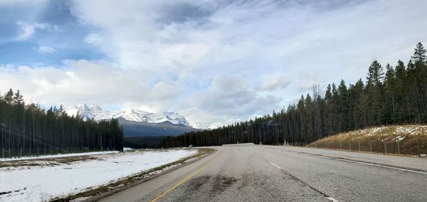 Road amidst trees against sky during winter