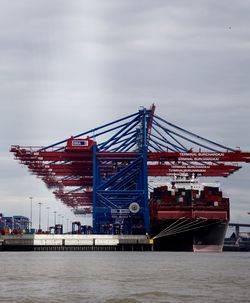 Cranes at commercial dock against sky