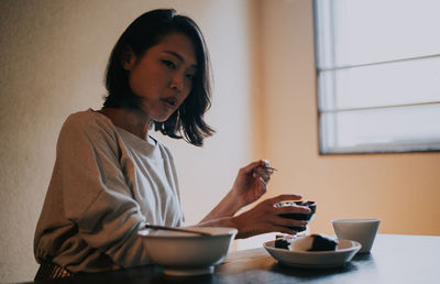 Beautiful woman eating food sitting at home