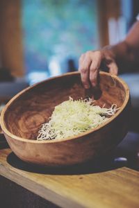 Midsection of person preparing food in bowl on table