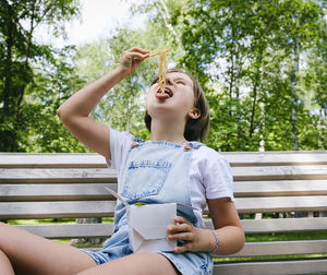 Teenage girl on a walk on a summer day in the park has lunch with noodles wok