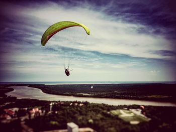 Person paragliding over sea against sky