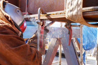 Midsection of man welding metal in factory