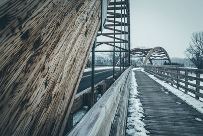 Snow covered footbridge against sky