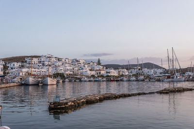 Sailboats moored in sea against sky in city