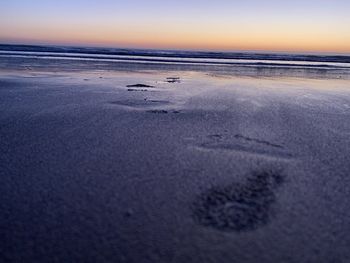 Surface level of beach against sky during sunset