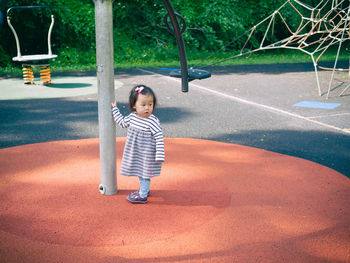 Girl looking away while standing by pole at park