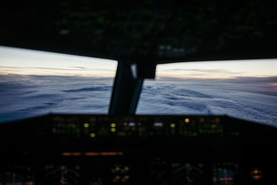 Airplane window against sky during sunset