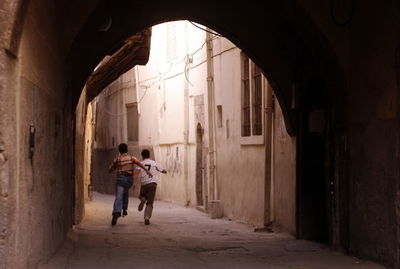 Rear view of boys running in alley