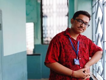 Portrait of young man standing against wall