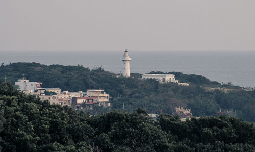 Lighthouse by sea against clear sky