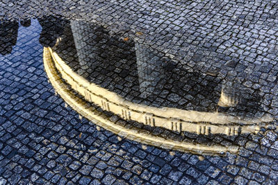 Reflection of building in puddle on footpath 