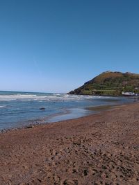 Scenic view of beach against clear blue sky