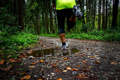 Low section of man running on road in forest