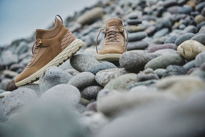 A pair of brown leather waterproof trekking boots on a sea coast. hiking concept.