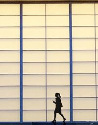Side view of man walking against wall