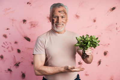 Portrait of smiling young man standing against plants