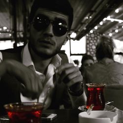 Portrait of man drinking glass on table at restaurant