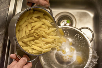 Midsection of person preparing pasta in kitchen