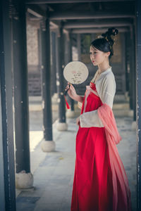 Young woman holding umbrella standing in corridor