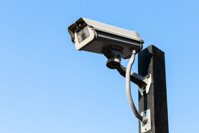 Low angle view of telephone pole against clear blue sky