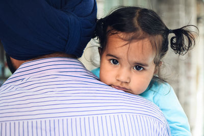 Rear view of father carrying cute daughter at home