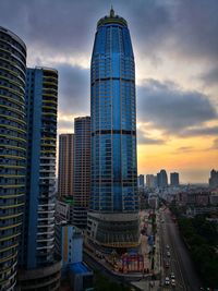 Modern buildings in city against sky during sunset