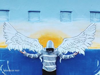 Rear view of man standing against graffiti wall