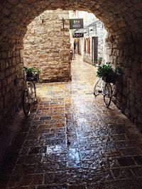 Bicycle on wet street amidst buildings during rainy season