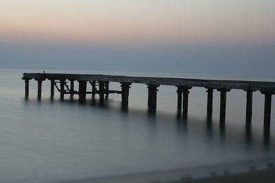 Bridge over sea against sky during sunset