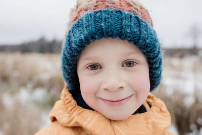 Portrait of a young boy smiling whilst playing outside in winter
