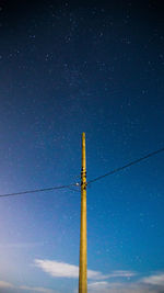 Low angle view of electricity pylon against star field