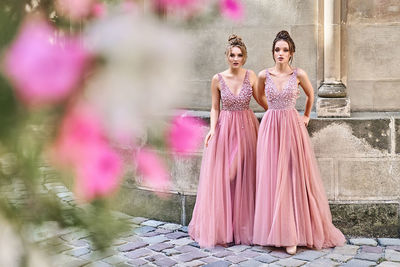 Portrait of woman standing against pink wall