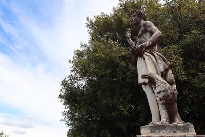 Low angle view of statue against trees against sky