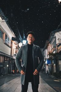 Portrait of young man standing in city at night