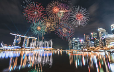 Firework display over illuminated buildings in city at night