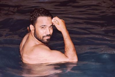 Portrait of shirtless man swimming in sea