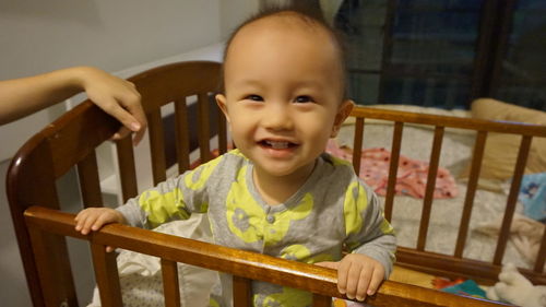 Portrait of cute baby boy standing in crib