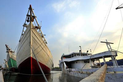 Sailboats moored at harbor against sky