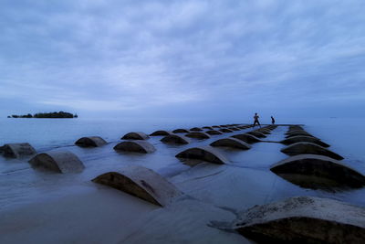 Scenic view of rocks at beach against sky