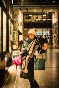 Portrait of mature woman with digital camera standing in corridor