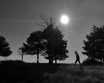 Silhouette man walking on field against sky