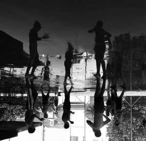 Reflection of silhouette people on swimming pool against sky