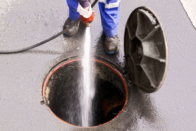 Low section of man cleaning manhole
